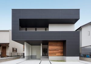 Fachada moderna de casa com revestimento escuro e detalhes em madeira.