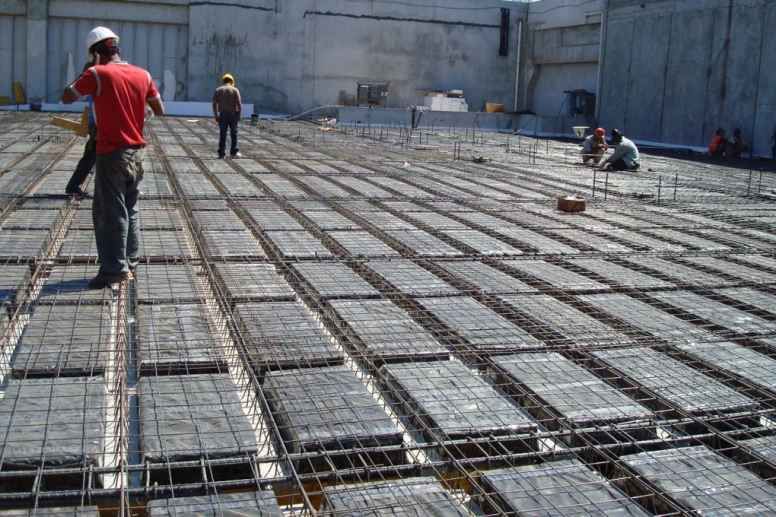 Trabalhadores inspecionando a estrutura de aço para laje com blocos de EPS.